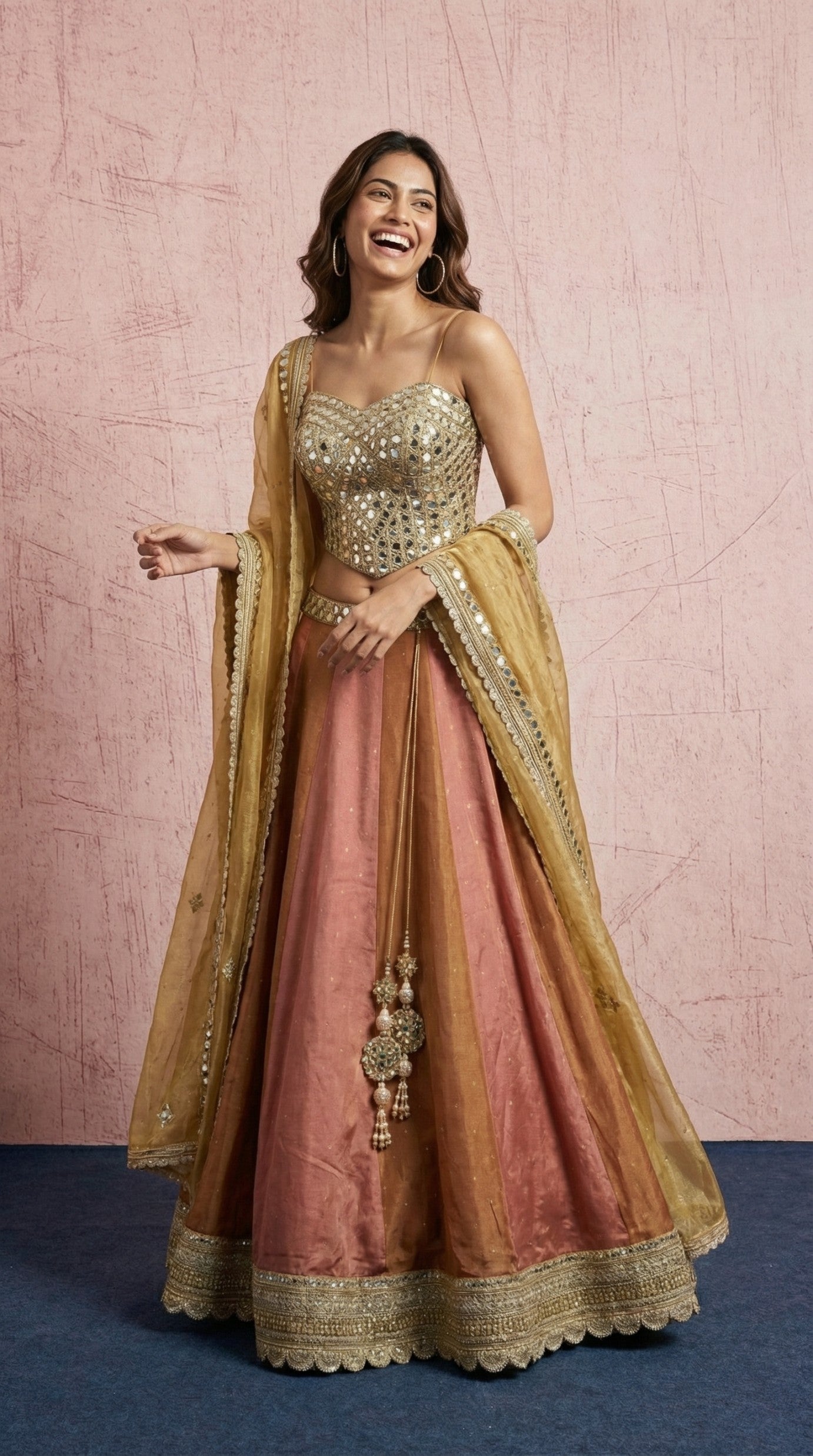 Woman wearing a traditional outfit with a pink and gold color scheme against a pink background