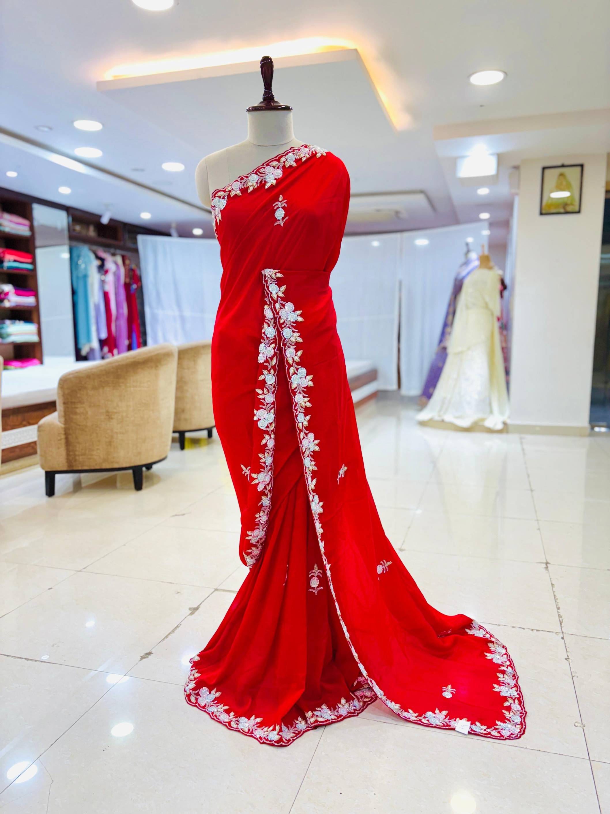 Red saree with white embroidery on a mannequin in a store setting