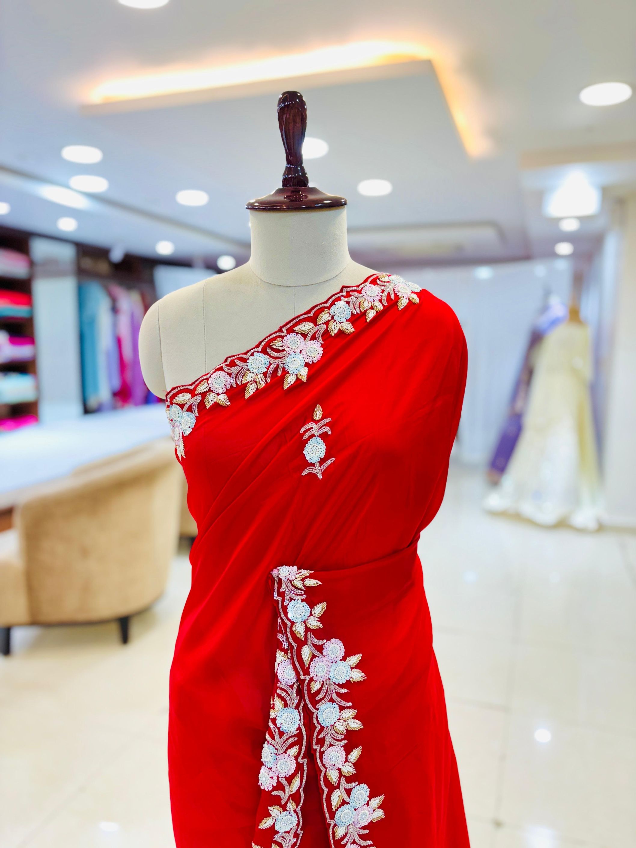 closeup of a Red saree with white embroidery on a mannequin in a store setting