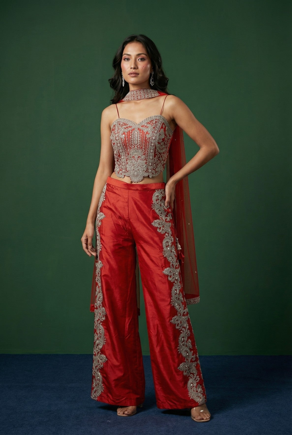 Woman wearing a ORANGE outfit with intricate silver detailing against a green background
