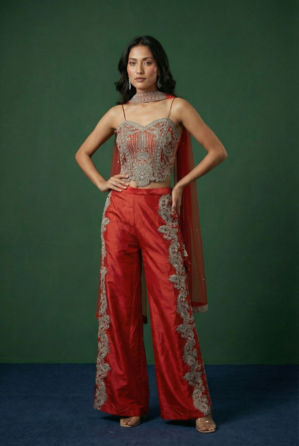 Woman wearing a ORANGE outfit with intricate detailing against a green background